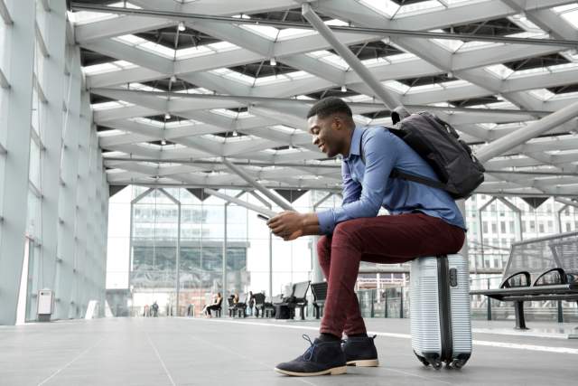 Man sitting in airport with smartphone